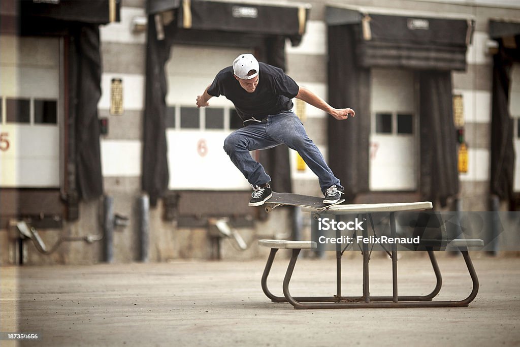 SKATEUR faire Crooked Grind sur une table de pique-nique - Photo de Faire du skate-board libre de droits