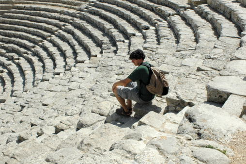 tourist sitting in the Segesta Amphitheater, Sicily, Italy