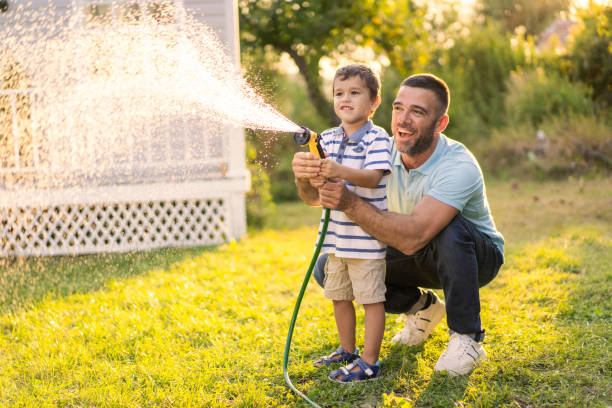 istock A man and boy both holding a garden pipe as they water the grass 1873569623