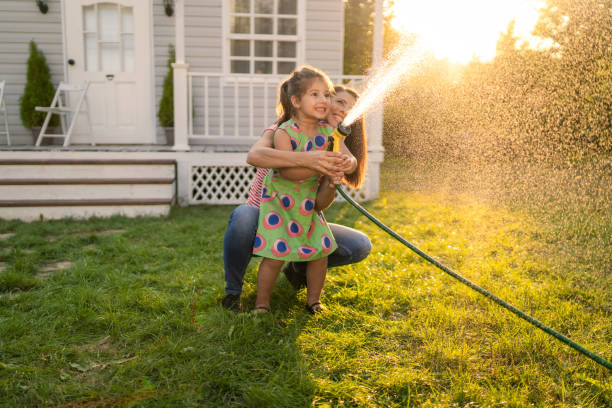 istock A mother and daughter watering the grass with hosepipe 1873569629