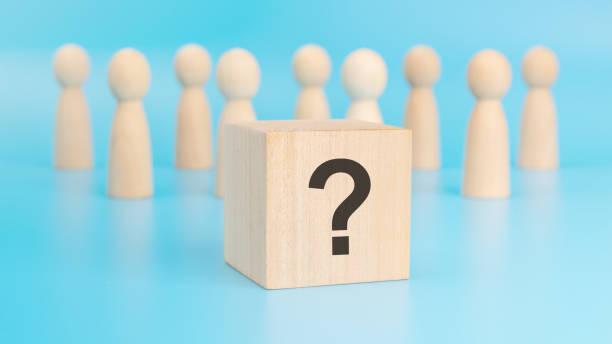 istock wooden cube with question mark on a blue table amid wooden figurines, representing business and education. the close-up focuses on the cube 1873574095