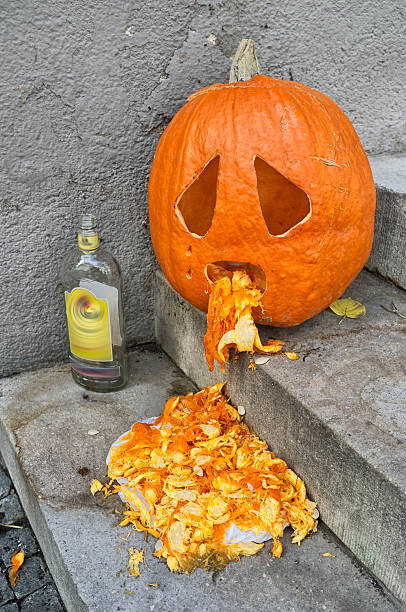 Vomiting Pumpkin Halloween pumpkin apparently vomiting seeds next to an empty bottle of alcohol. throwing up pumpkin stock pictures, royalty-free photos & images