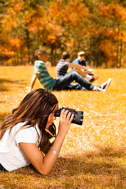 istock Teenagers:  Spectators in park.  One watching with binoculars, others talking. 187362956