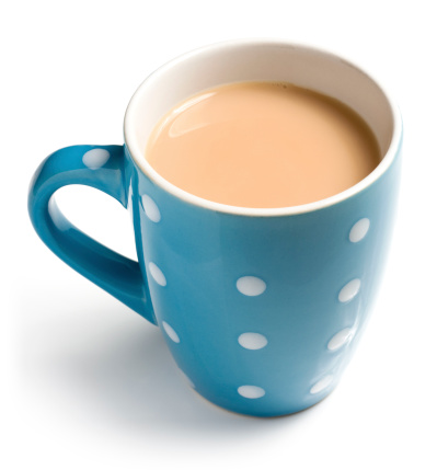 English breakfast tea with a splash of milk in a blue mug with spots isolated on a white background. English breakfast tea is a black tea used to make aromatic beverage. The drink is prepared by pouring boiling water over a tea bag or tea leaves which is left to brew. Tea with milk and sugar is also known as builders tea, a cuppa or a brew.