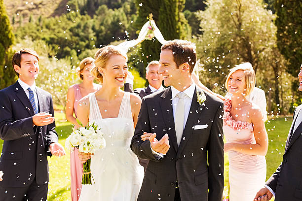 Guests Throwing Confetti On Couple During Garden Wedding Happy wedding guests throwing confetti on newlywed couple after wedding ceremony in garden. Horizontal shot. wedding reception photos stock pictures, royalty-free photos & images