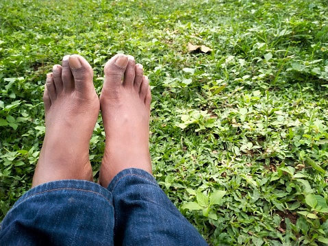 An adult leg in jeans is sprawled out on the weeds