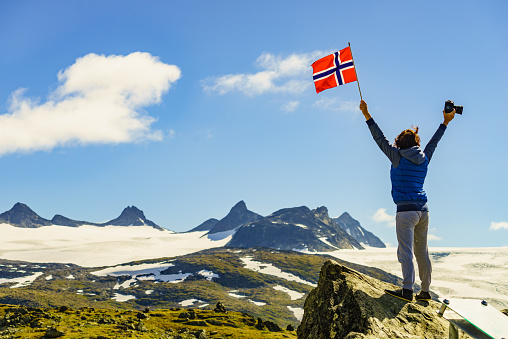 He is sitting below a Swiss flag and glaciated mountains