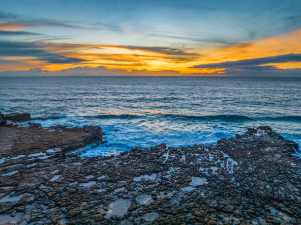 istock Sunrise over the sea and rock platform with high cloud 1873673375
