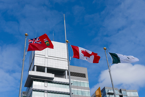 The flag of Ontario, Flag of Canada and Flag of the City of Kitchener waving in the wind at Kitchener City Hall.