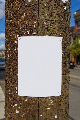 Blank poster on a wooden post with lots of nails on it