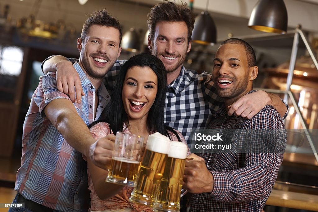 Gruppo di amici felici di quel fastidioso tintinnio di birra al pub - Foto stock royalty-free di 25-29 anni