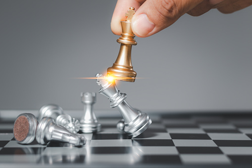 Businessman moving chess king on chess board game for competition and planning strategy, business competition planning teamwork strategic concept.