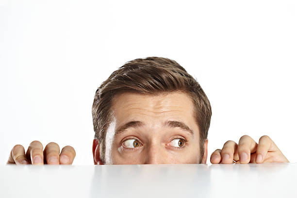 hombre curioso disfrutando de una mesa. - hiding fear men peeking fotografías e imágenes de stock