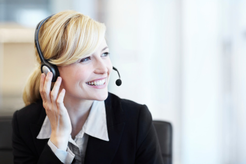 A helpful call center agent assisiting a client with a smile on her face