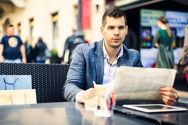 istock Young man having a break and reading newspaper 187386470