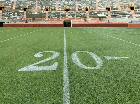 Wide angle view of a20 yard line in a football stadium with fulllbleachers