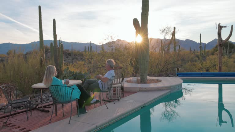 Mature couple enjoy sunrise moments by desert pool