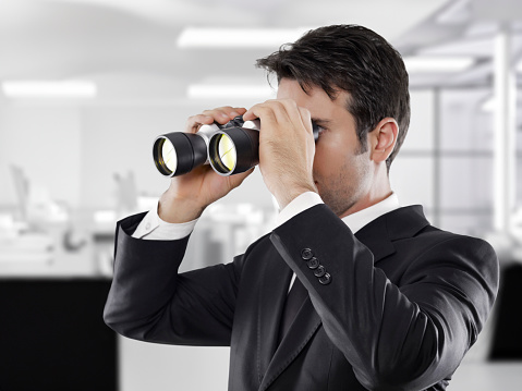 Businessman with binoculars is looking for new business ideas.