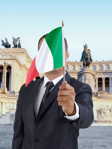 Businessman holding an Italian flag in front of Vittorio Emanuele II monument in Rome