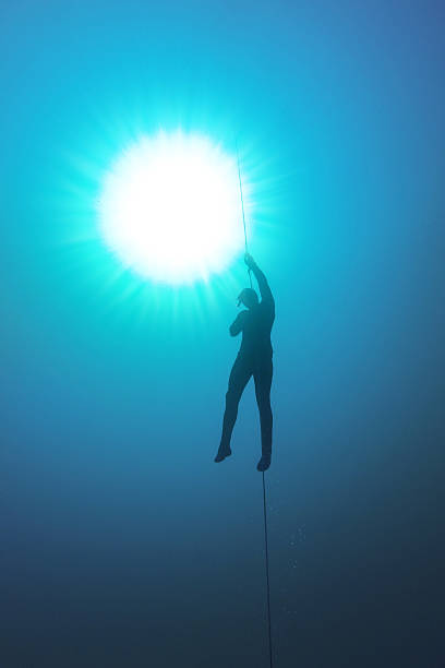 Freediver holding a rope and his breath in the water stock photo