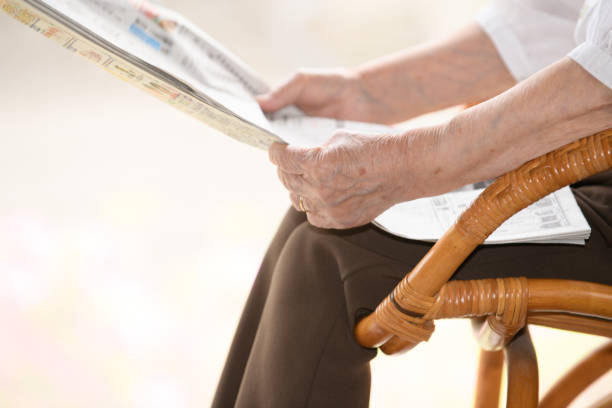 istock elderly woman reading a newspaper 1873875524
