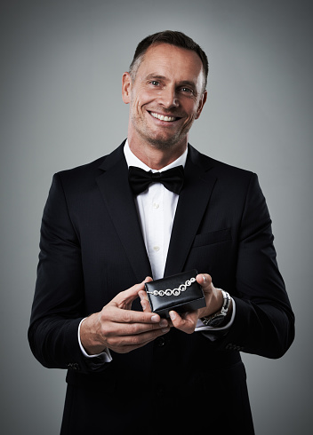 Portrait of a handsome man holding up a diamond necklace to the camera