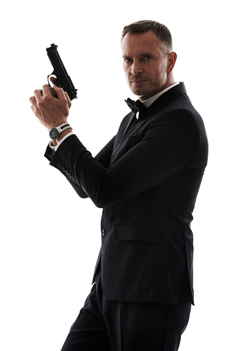 A handsome man in a suit holding a gun