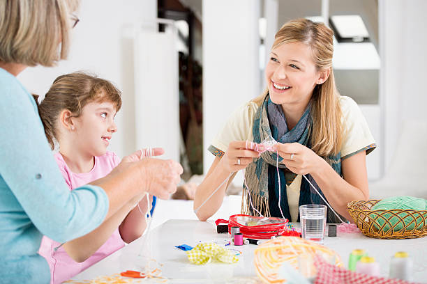 Senior woman teaches her granddaughter how to measure cloth for sewing, they are using measure tape and chalk