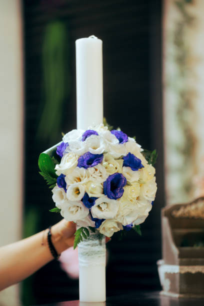 istock Hand holding a Baptismal Candle with Floral Arrangement 1873977907