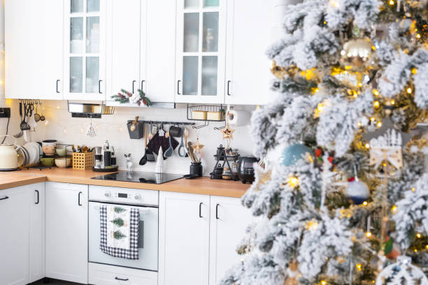 istock Festive Christmas decor in white kitchen, modern rustic interior with a snowy Christmas tree and fairy lights. New Year, Christmas mood, cozy home. The general plan 1874003750