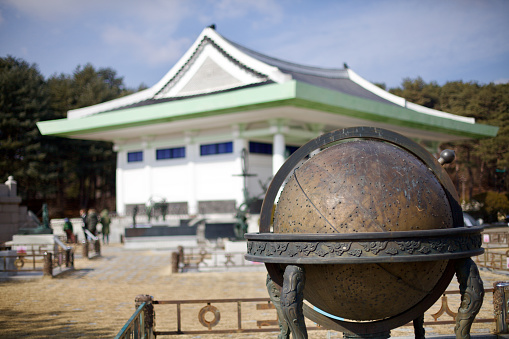 Yeoju City, South Korea - February 16, 2020: A striking globe sculpture stands prominently before the slightly blurred backdrop of King Sejong's Tomb museum.