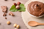 Milk chocolate and hazelnut cream on wooden table with tablecloth