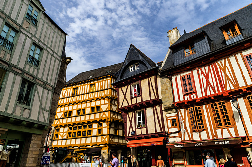 Immerse yourself in the captivating charm of historic Vannes through this photograph, where the cobblestone streets weave a tapestry of bygone eras. The narrow lanes, lined with half-timbered houses adorned with blooming window boxes, exude an ageless allure. As sunlight bathes the timeworn facades in a warm glow, the architectural details of centuries past come to life.

Quaint storefronts, inviting cafés, and hidden boutiques beckon to passersby, inviting exploration and discovery. The medieval architecture, with its timber-framed structures and ornate carvings, stands as a testament to the enduring beauty of Vannes' rich history. Towering spires and ancient city walls provide a backdrop to this scene, adding to the timeless ambiance of the streets.

The atmosphere is one of a living canvas, where every stone tells a story and each corner reveals a piece of the city's heritage. This image captures the essence of Vannes' historic streets, inviting viewers to wander through the labyrinth of time and embrace the unique blend of architectural elegance and rustic charm that defines this picturesque Breton town.