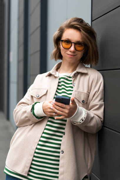 istock Young girl with smartphone outdoors portrait, looking at camera 1874052929