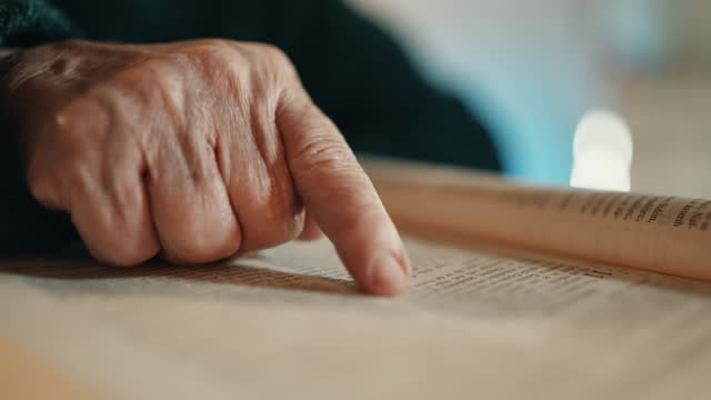 SLO MO Closeup of Senior Woman Following with her Finger Reading Holy Bible at Home