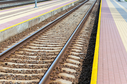 Railroad tracks urban shoot. Leading line view.iron rusty train railway detail over dark stones rail way