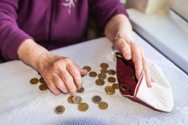 vecchia donna seduta miseramente a casa e contando le monete rimanenti della pensione nel suo portafoglio dopo aver pagato le bollette. - miseramente foto e immagini stock