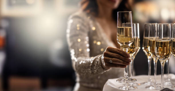 un barista tiene in mano un piatto con champagne rosa e una donna in abito da cocktail prende uno dei bicchieri a un evento, una festa o un matrimonio. - champagne wedding luxury dinner foto e immagini stock