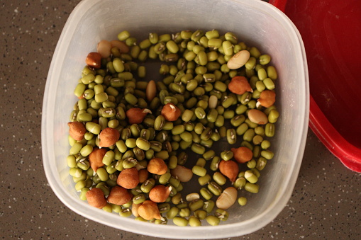 Mix of salad of several moong dal urad daal and chik peas channna in the plastic container, top shot
