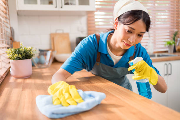 professionelle asiatische frau reinigungsservice trägt gelbe gummihandschuhe und wischt mit einem lappen mit flüssigem reinigungsmittel auf der hölzernen küchenarbeitsplatte zu hause ab. reinigung des haushalts, asiatisches dienstmädchen. - cleaning domestic kitchen counter top housework stock-fotos und bilder