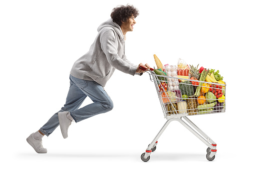 Young man running with food in a shopping cart isolated on white background