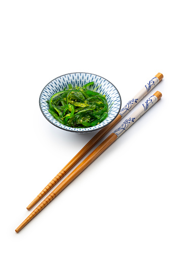 Organic Japanese Wakame salad in a bowl with chopsticks isolated on white background, high angle view, studio shot.