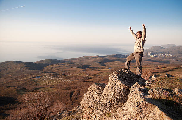 istock Man pumping fists while standing on desert rock formation 187417125