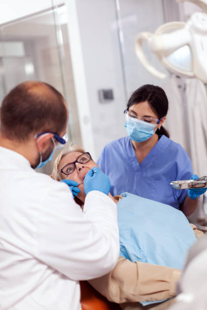 istock Dentist with assistant install implant in patient mouth 1874196905