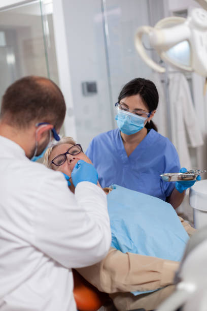 istock Dentist with assistant install implant in patient mouth 1874201698