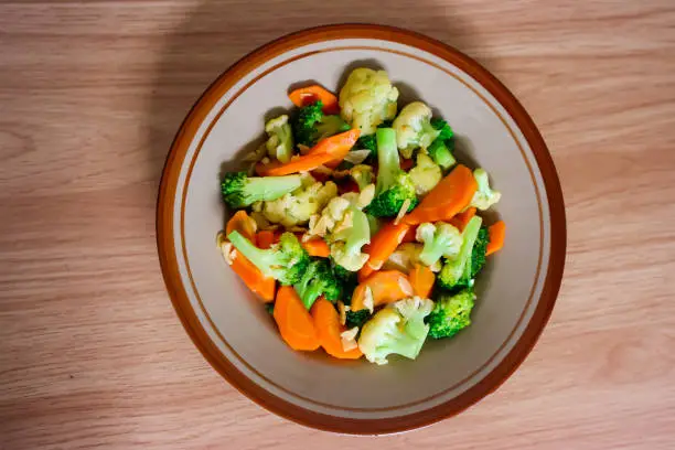 Sauteed vegetables of carrot, brocoli, and cauliflower serving on a ceramic plate. Healthy food concept