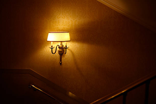 Glowing lamp hanging on hotel staircase wall.
