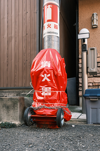 Covered community fire extinguisher in a street against a pole.