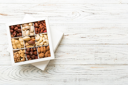 Various varieties of nuts lying in paper box on table background. Top view. Healthy food. Close up, copy space, top view, flat lay. Walnut, pistachios, almonds, hazelnuts and cashews.