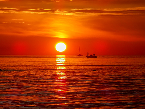 Fiery sky at sunset over a fishing boat in the calm sea